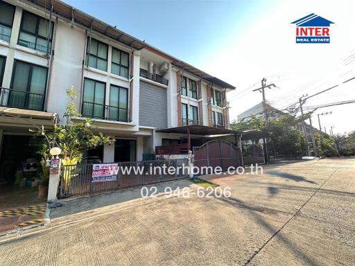 Exterior view of a modern townhouse with paved driveway and carport