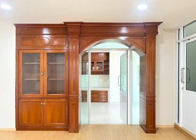 Elegant archway leading from a wooden furnished living room to a modern kitchen