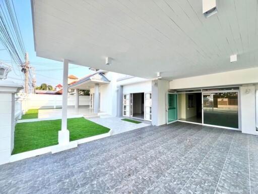 Spacious covered patio with tiled flooring and artificial grass area