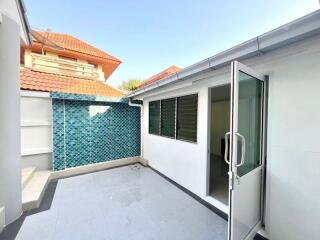 Spacious tiled patio with a glass door and blue mosaic tile wall