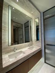 Modern bathroom interior with elegant marble finish and well-lit mirrors