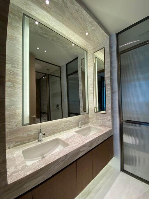 Modern bathroom interior with elegant marble finish and well-lit mirrors