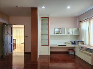 Spacious and well-lit living room with wooden flooring and built-in shelves