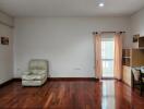 Spacious and bright living room with hardwood floors, minimal furnishings, and balcony access