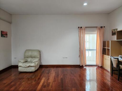 Spacious and bright living room with hardwood floors, minimal furnishings, and balcony access