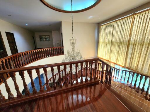 Elegant hallway with wooden railing and a grand chandelier