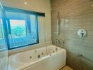 Modern bathroom with bathtub and shower near a large window overlooking greenery