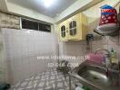 Old style kitchen with tiled walls and basic appliances