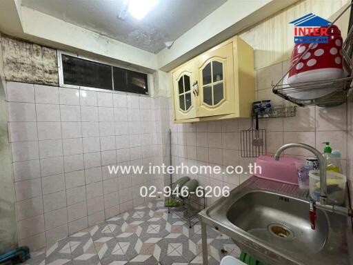 Old style kitchen with tiled walls and basic appliances