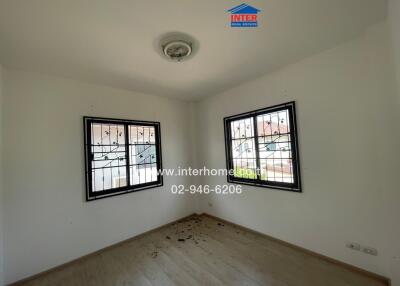 Empty bedroom with large windows and wooden flooring