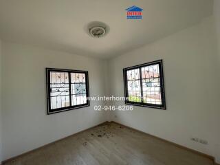 Empty bedroom with large windows and wooden flooring