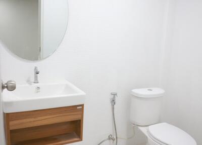 Clean and modern bathroom with white walls, wooden vanity, and ceramic fixtures