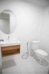 Clean and modern bathroom with white walls, wooden vanity, and ceramic fixtures