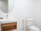 Clean and modern bathroom with white walls, wooden vanity, and ceramic fixtures