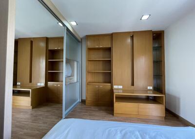 Spacious bedroom with extensive built-in wooden wardrobes and laminate flooring