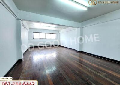 Spacious empty room with wood flooring and fluorescent lighting