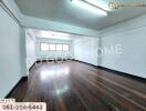 Spacious empty room with wood flooring and fluorescent lighting