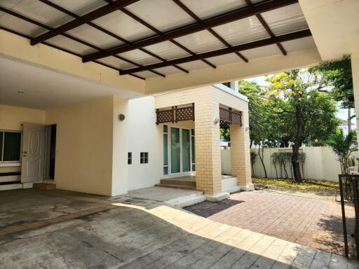 Spacious front yard of a modern home with covered parking and lush greenery