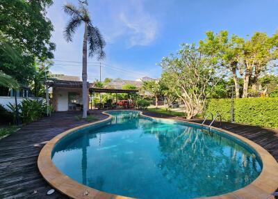Lush outdoor swimming pool area with adjacent wooden decking and tropical landscaping
