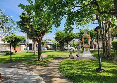 Lush green park in residential community with walking paths and a shrine