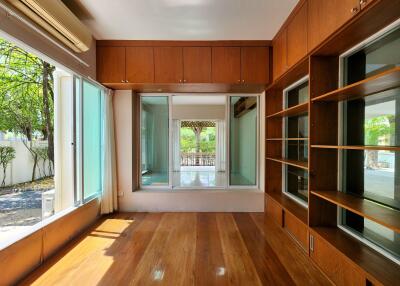 Spacious living room with hardwood floors, large windows, and built-in shelving