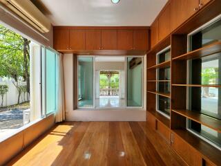 Spacious living room with hardwood floors, large windows, and built-in shelving