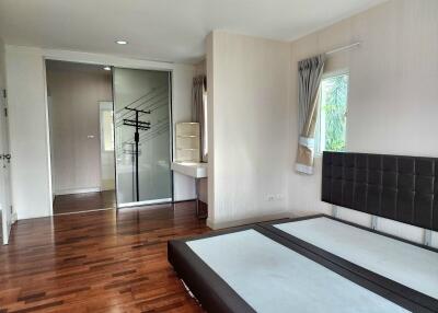 Spacious bedroom with wooden flooring and large glass wardrobe