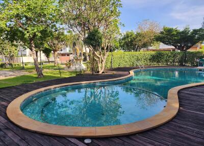 Elegant outdoor pool with wooden decking and lush greenery