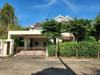 Exterior view of a two-story house with a covered driveway and lush greenery