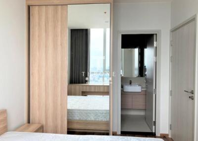 Modern bedroom with view into ensuite bathroom and city view