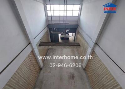 Wide hallway in a commercial or industrial building with high ceiling and natural light