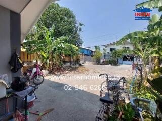 Spacious outdoor area with lush greenery and parking space