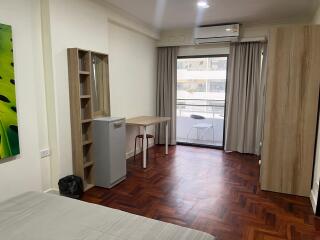 Spacious bedroom with wooden flooring and natural light