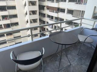 Modern balcony with a table and two chairs overlooking city buildings