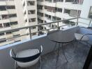 Modern balcony with a table and two chairs overlooking city buildings