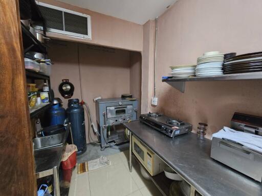 Compact commercial kitchen with various appliances and storage shelves