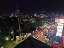 Nighttime view from balcony showing busy street and illuminated buildings