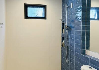 Modern bathroom with blue tile shower and white fixtures