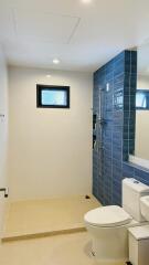 Modern bathroom with blue tile shower and white fixtures