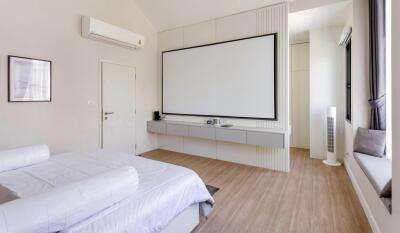 Spacious and modern bedroom with large bed and projector screen