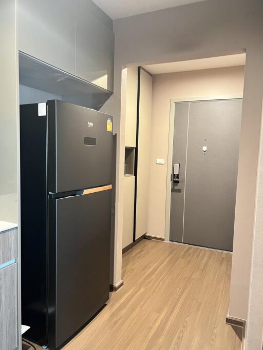 Modern kitchen with black refrigerator and wooden flooring near entrance