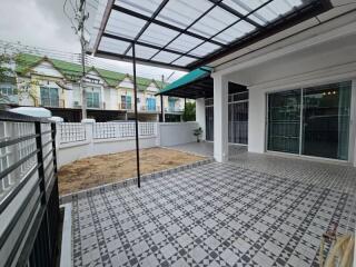 Spacious tiled patio with partial roofing adjacent to residential buildings