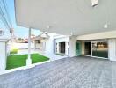 Spacious covered patio with modern flooring and landscaped lawn