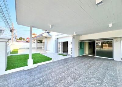 Spacious covered patio with modern flooring and landscaped lawn