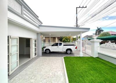 Modern white residential house exterior with carport and landscaped lawn