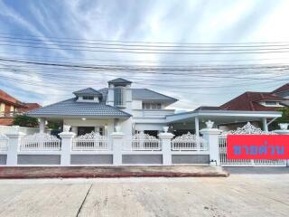 Elegant two-story house with a white fence and detailed architecture under a bright sky