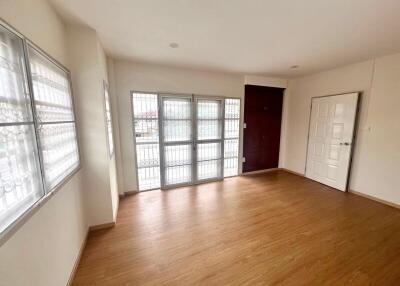 Spacious and well-lit living room with large windows and wooden flooring