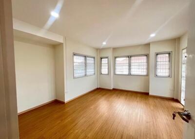 Spacious and bright empty living room with wooden flooring and multiple windows