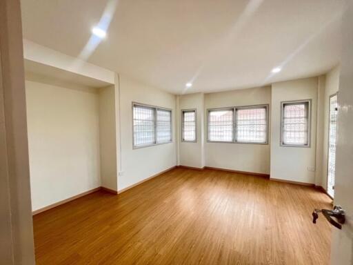 Spacious and bright empty living room with wooden flooring and multiple windows