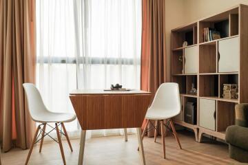 Modern bedroom with a study area featuring a wooden desk and two white chairs